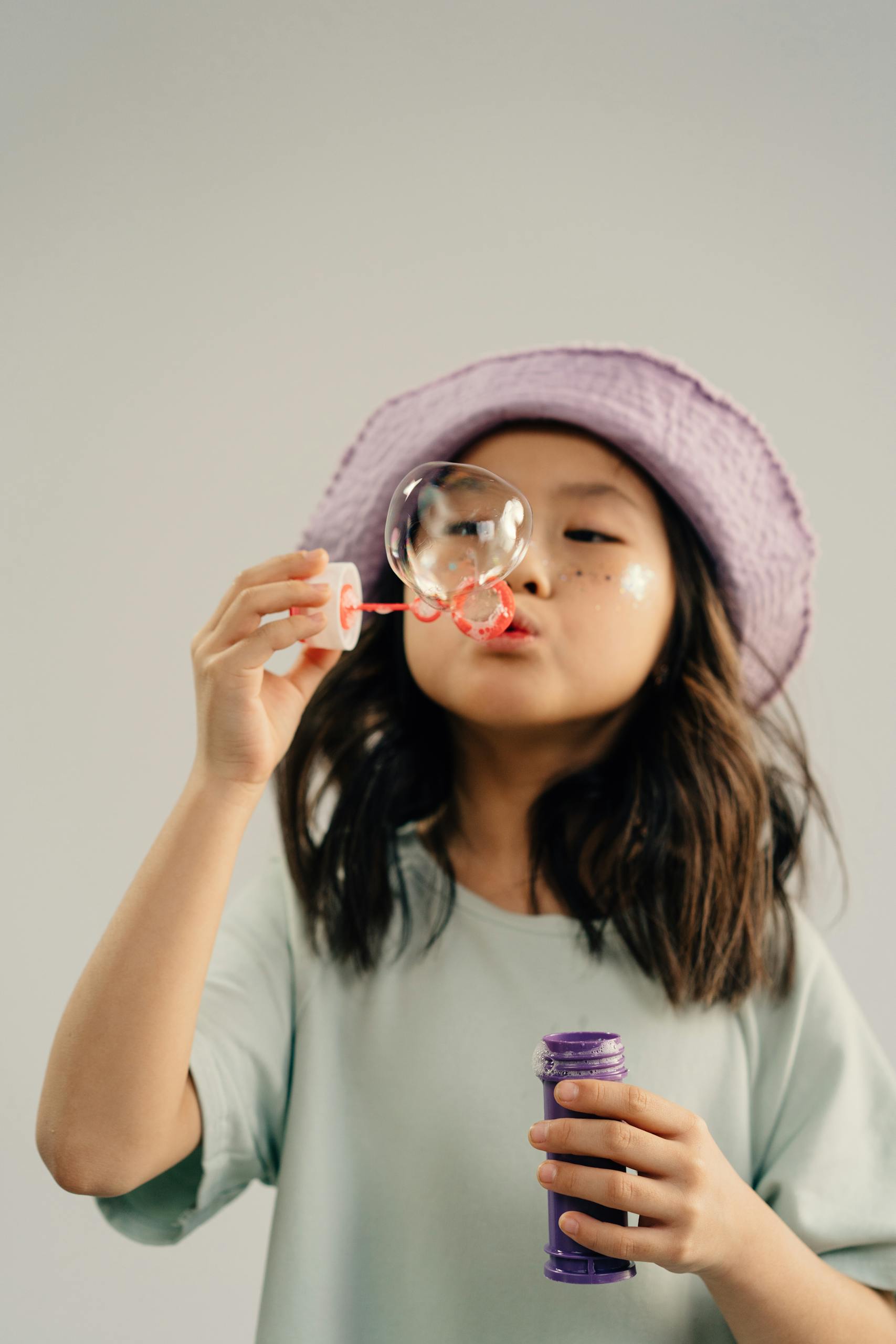 Child enjoying playing with bubbles in a studio setting.